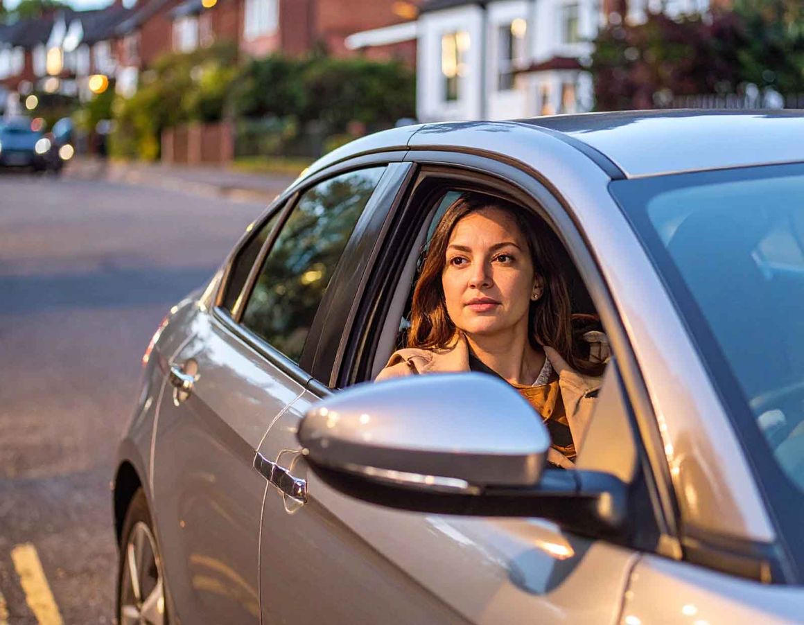 A woman observes surroundings from her parked car